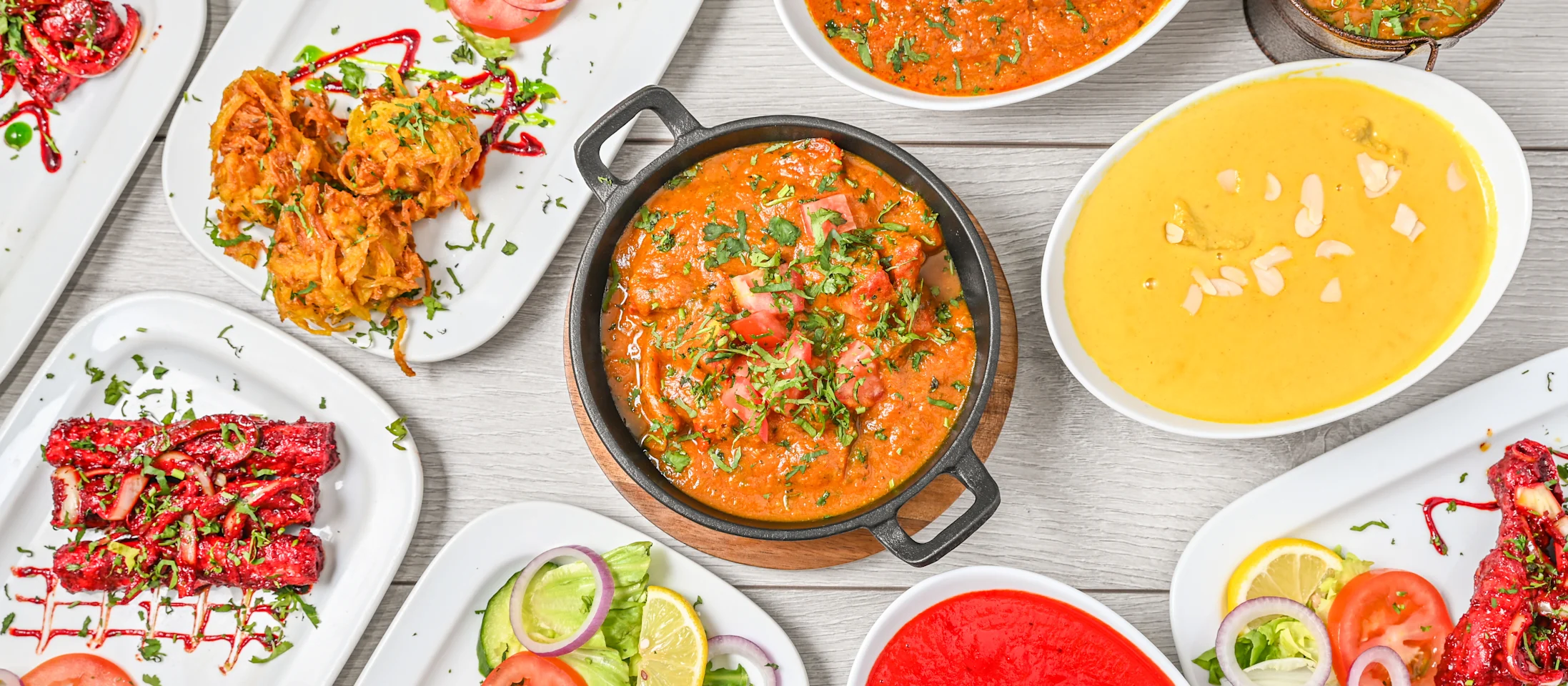 A spread of freshly cooked Indian dishes at Spice of India Dublin: curries, tandoori starters, onion bhaji and salad